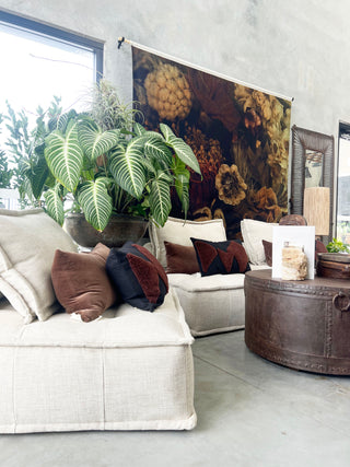 Living room with a large tapestry on the wall, white sofa with brown and blue cushions, and decorative items.