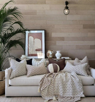 Living room with a beige sofa, decorative pillows, and a wooden wall.
