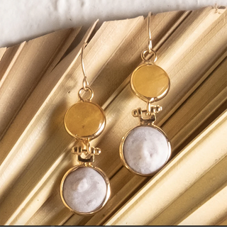 Gold and stone earrings on a textured gold surface