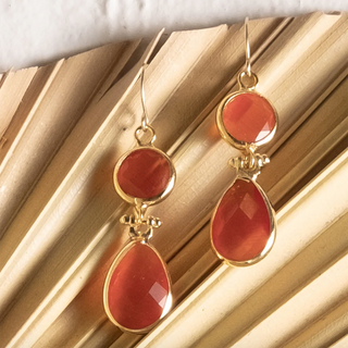 Gold earrings with red stones on a gold surface