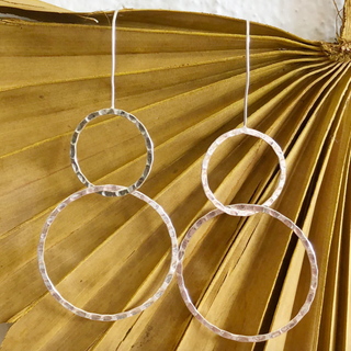 Silver hoop earrings hanging against a textured gold background