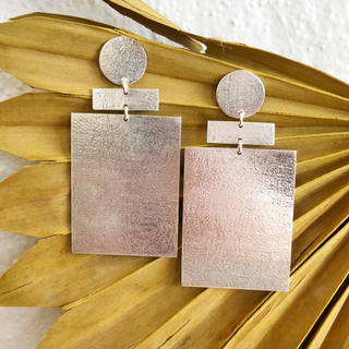 Silver earrings on a textured gold leaf background