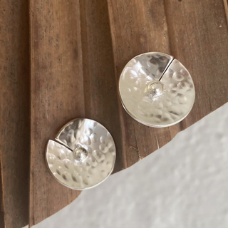 Pair of silver round earrings on a wooden surface