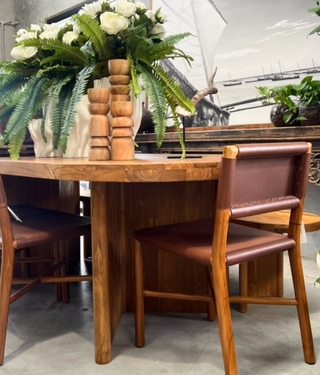 Wooden dining table with chairs and a vase of flowers in a room setting.
